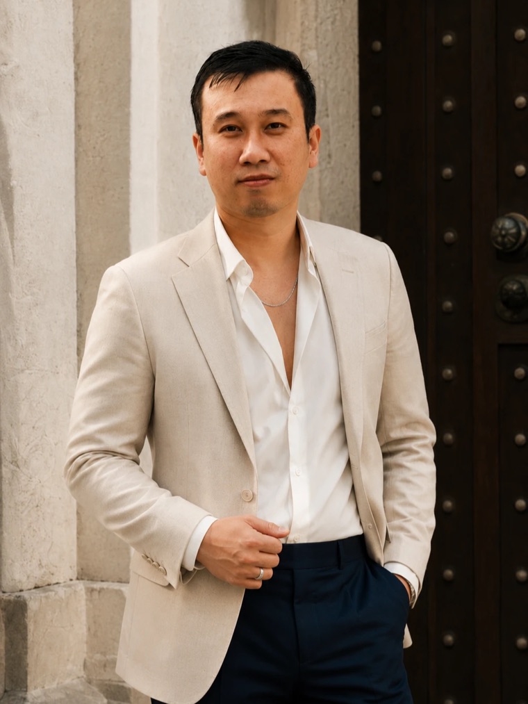 Nguyen Thanh Nghiep in a linen blazer, standing by a stone wall and a wooden door
